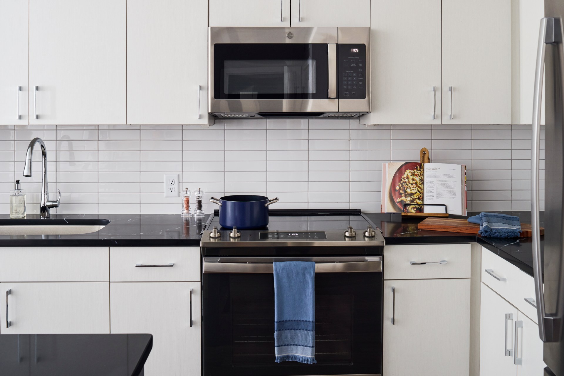 Black granite countertops & stainless steel appliances in apartment kitchen at Aster College Park, MD